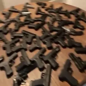 The image shows a table covered in a large number of handguns.